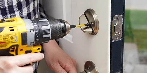 Hand using a drill to install a lock on a door, highlighting the benefits of professional lock installation in Weddingon, NC.