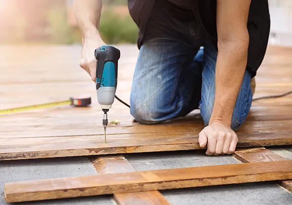 Person installing a wooden deck, showcasing expert deck assembly services in Waxhaw, NC