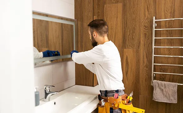 Technician installing or adjusting a wall-mounted cabinet or mirror in a modern kitchen setting.