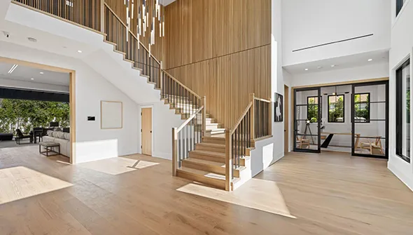 Spacious, well-lit modern interior with wooden staircase, light hardwood floors, and minimalist furniture depicting a clean home environment.