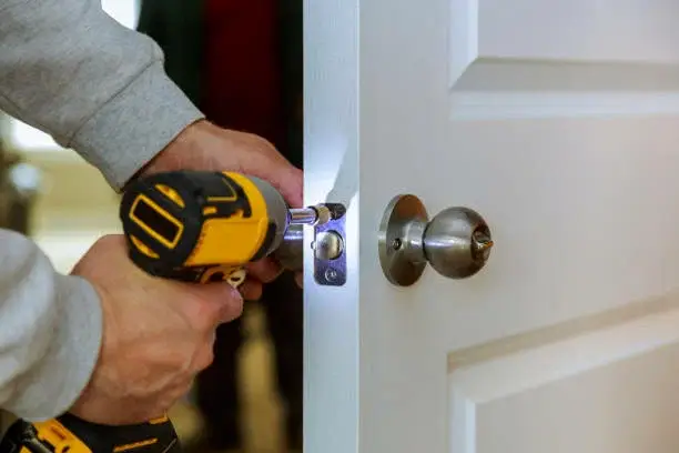 The worker is installing door lock in Charlotte, NC.