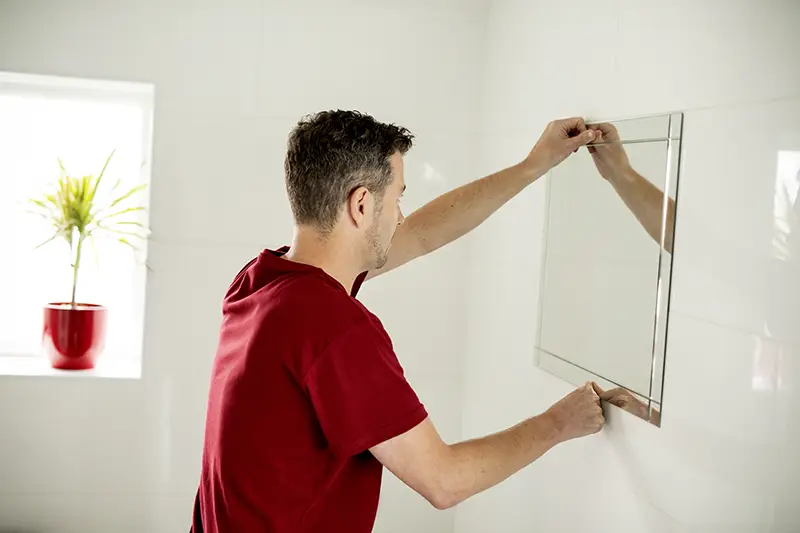 The man is hanging mirror in Weddington, NC.